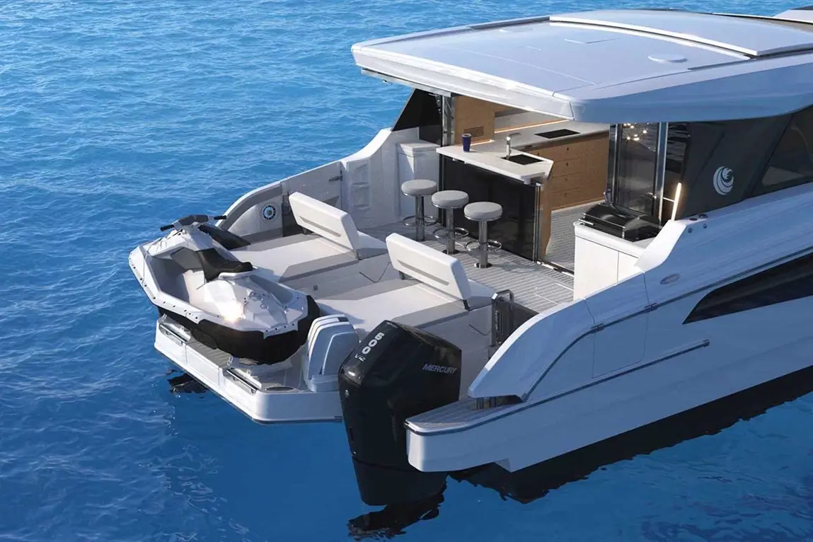 A luxury yacht with a jet ski is anchored in blue water, featuring outdoor seating, a small kitchen, and modern design elements.